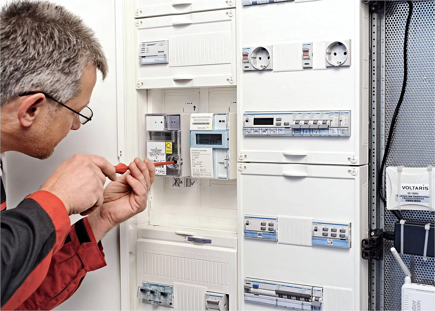 Ein Monteur installiert einen Smart Meter in einem Stromkasten